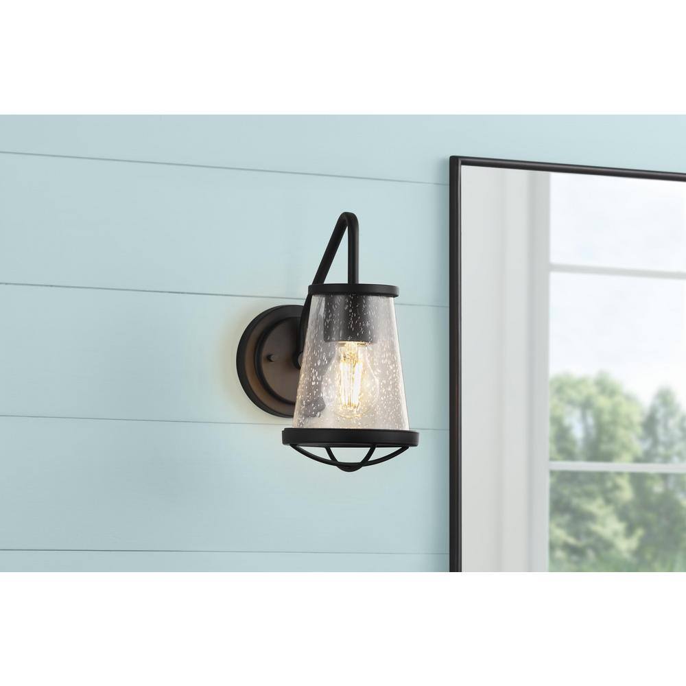 Home Decorators Collection Georgina 5.75 in. 1-light Matte Black Industrial Indoor Wall Sconce with Clear Seeded Glass Shade